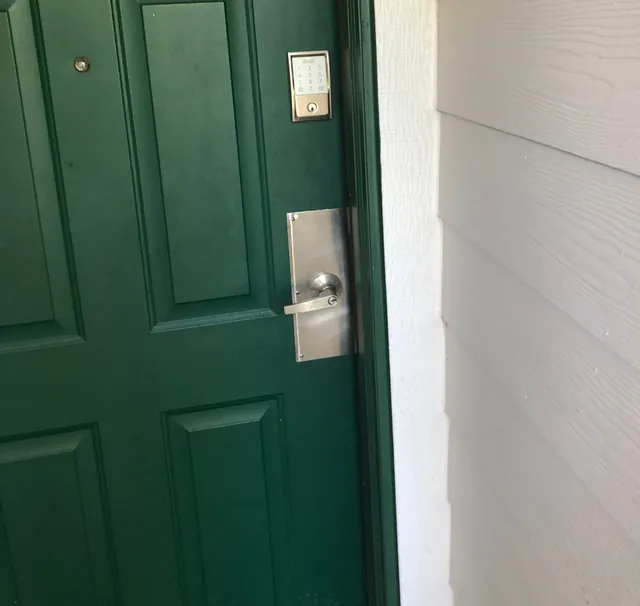 Green entry door with a keypad lock and a lever on a stainless plate