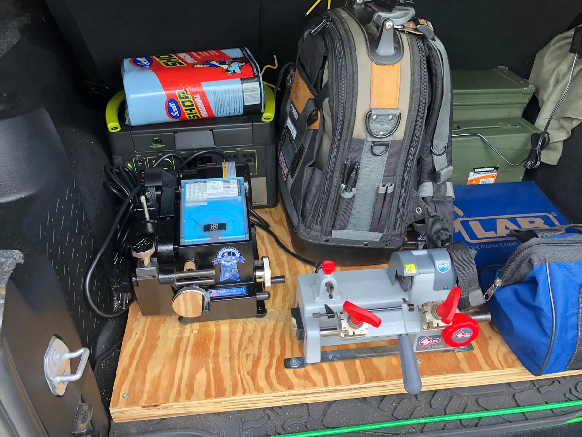 Inside the Sterling Locksmiths Jeep: an HPC Blitz code machine, a Silca key duplicator, a LAB pinning kit, a tool backpack and a portable power station on a plywood work deck